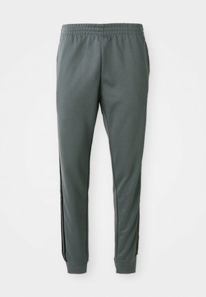 Grå joggerbukser med elastisk talje, tapered ben og sorte sidelister, lavet af et glat, strækbart stof.