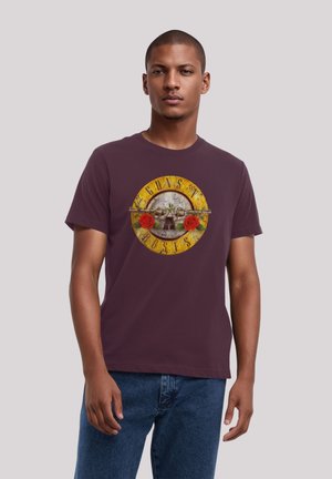 Maroon unisex t-shirt featuring a circular graphic with a skull, roses, and the text "Guns N' Roses" in yellow, red, and gray tones.