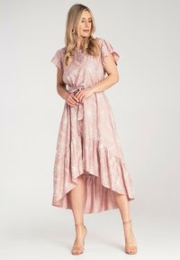 Różowa, zwiewna sukienka z białymi wzorami florystycznymi, krótkimi falbaniastymi rękawami, wiązanym w pasie oraz asymetrycznym dołem. Wykonana z lekkiego materiału.