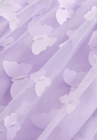 Lila tylltyg med vita fjärils mönster och silvertråds detajer, lager på lager för textur och djup.