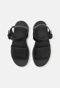 Černé kožené sandály s dvěma širokými popruhy, nastavitelným nártem a polstrovanou podrážkou pro pohodlí. Hladká textura, minimalistický design.