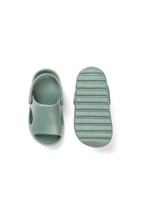 Vihreät kumiset sandaalit, joissa avoin varvasosa, teksturoitu pohjallinen ja uritettu pohja pitoon. Kevyet ja sivuilta viilennetyt.