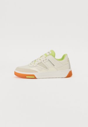 Sneakers with a beige leather upper, lime green accents, perforated detailing, and an orange rubber sole. Lace-up closure and structured design.