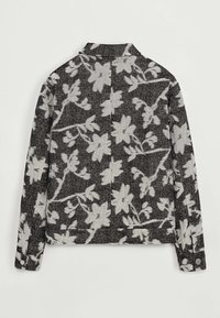 Veste à motifs floraux en noir et gris, fabriquée en tissu texturé. Elle présente un col, des manches longues et des détails de boutons aux poignets.