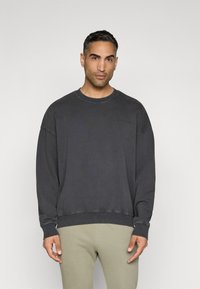 Sweatshirt cinza carvão com um corte descontraído, decote redondo e punhos canelados, apresentando um logotipo discreto no peito. Textura suave e macia.