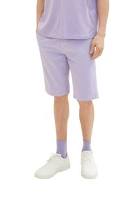 Pantalones cortos de lavanda fabricados con un tejido ligero, con un diseño de corte recto. Combinados con zapatillas blancas y calcetines de lavanda a juego.