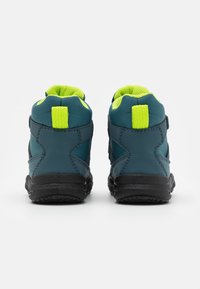 Niebieskie wysokie buty sportowe z czarnymi podeszwami i jaskrawozielonymi akcentami, wykonane z teksturowanego materiału i wzmocnionym wsparciem pięty.