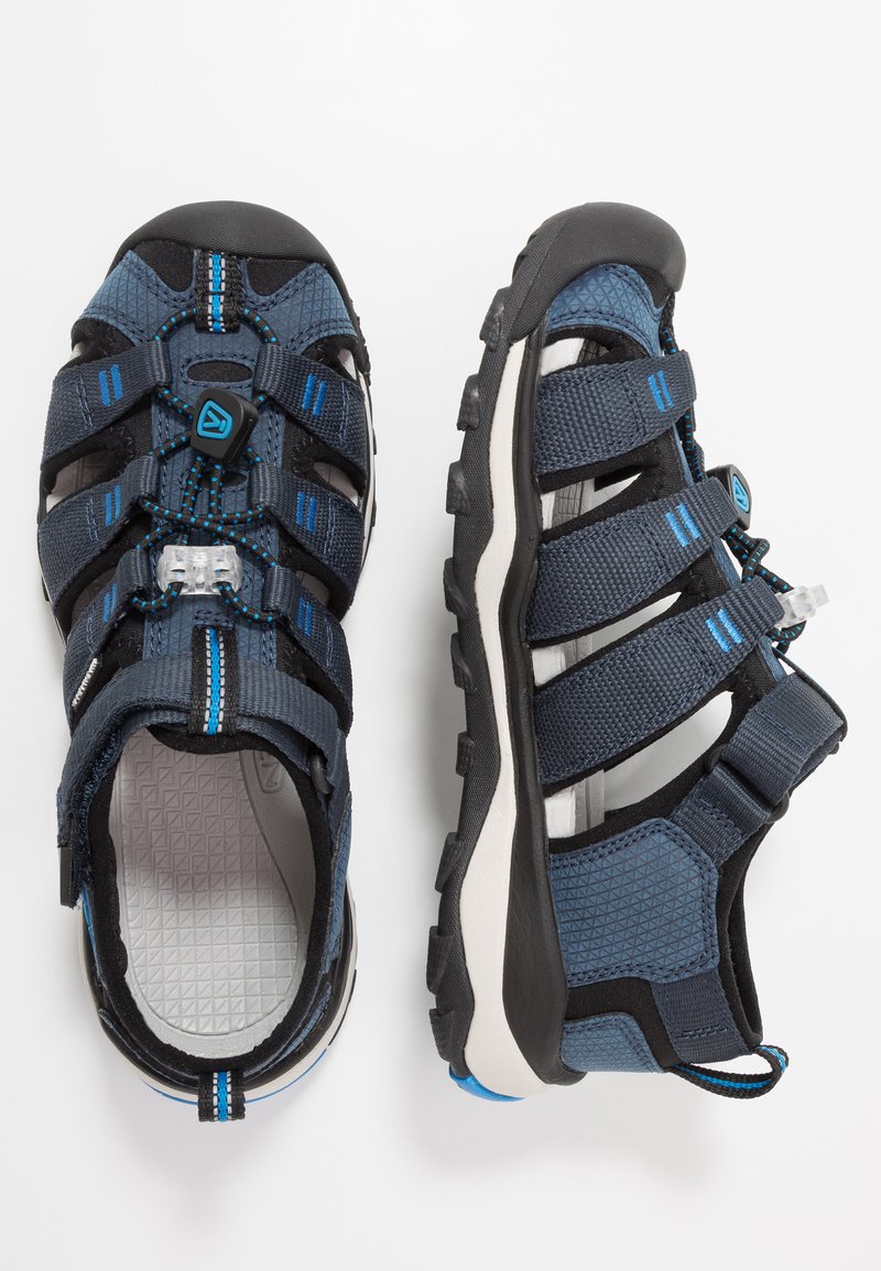 Sandálias desportivas para homem, parte superior em malha azul escuro e preta com tiras elásticas, sola em borracha e faixa de calcanhar ajustável. Interior texturizado.