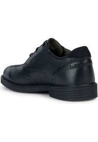 Svarta läderdresskor med broguedetaljer, rund tå och texturerad gummisula. Har snörningsdesign och vadderad krage.