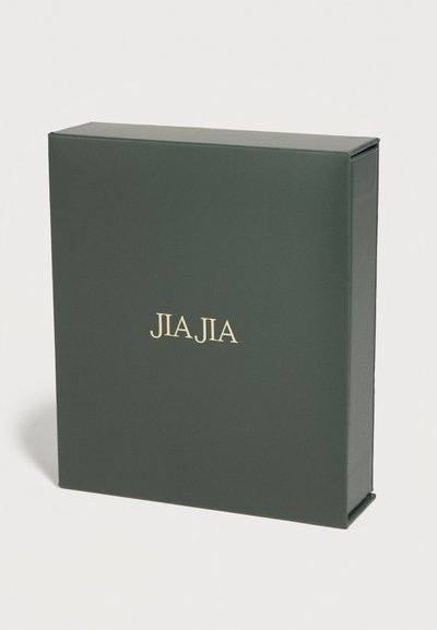 Σκούρο πράσινο ορθογώνιο κουτί με χρυσά γράμματα "JIA JIA" στο κέντρο της μπροστινής πλευράς, τοποθετημένο σε λευκή επιφάνεια.