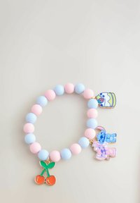 Színes gyöngy karkötő, amely világos rózsaszín és kék gömbgyöngyöket tartalmaz, mellette zománcozott cseresznye, torta és meseállatok charmokkal.