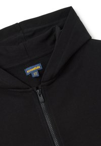 Felpa nera con zip realizzata in tessuto morbido; presenta un cappuccio, una chiusura lampo frontale e un'etichetta con la scritta "essentials" in blu e giallo.