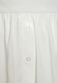 White blouse with a smooth texture, featuring a button closure and gathered fabric details. Classic design and soft, draping material.