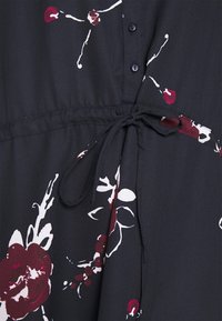 Schwarzes Kleid mit weißem und burgunderfarbenem Blumenmuster, ausgestattet mit Knöpfen, einem Bindegürtel und einer weichen, glatten Stoffoberfläche.