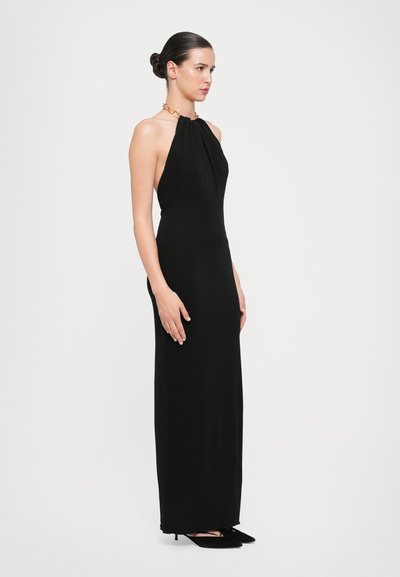 Sort halterneck-kjole med en tætsiddende silhuet, draperet stof og en gylden kæde accent ved halsudskæringen. Gulvlængde design, minimal detalje.