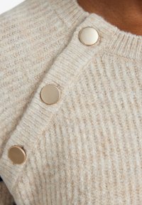 Beige Strickpullover mit geribbelter Textur, ausgestattet mit runden goldenen Knöpfen am Ausschnitt für sicheren Halt.