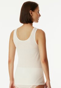 White ribbed tank top with a scooped back and narrow straps, made from a soft material, fitted design, and slight stretch for comfort.
