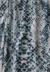 Textured fabric in shades of blue and white featuring a snake-skin pattern, with a small metallic logo tag visible.