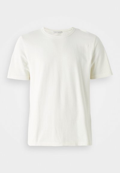 Gaišas krēms kokvilnas T-krekls ar apaļu kakla izgriezumu un īsām piedurknēm. Gluda tekstūra, vienkāršs dizains un brīvs piegriezums. Nav rakstu vai akcentu.