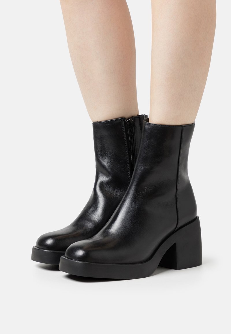Black leather ankle boots with a rounded toe, smooth texture, side zipper, and a chunky heel. Simple design with a clean silhouette.