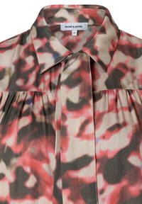Blouse à motif floral en tissu léger. Caractéristiques : col, fermeture à boutons et détails plissés dans des teintes de rouge, noir et crème.