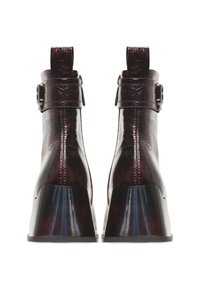 Bottines bordeaux brillantes avec une finition texturée, des talons noirs épais et des boucles réglables sur les côtés.