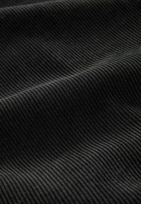 Schwarzer Cordstoff mit gerippter Textur, parallelen Rillen und einer weichen Oberfläche. Keine sichtbaren Muster oder Hardwaredetails.