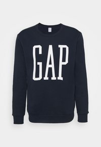 Marineblauwe trui van katoen, met een witte "GAP" logo in vette letters aan de voorkant. Klassieke ronde hals met ribboord aan de mouwen.