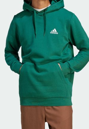 Grøn hættetrøje lavet af blødt stof, med en forlommekangaroo og hvidt Adidas-logo på brystet. Casual pasform.