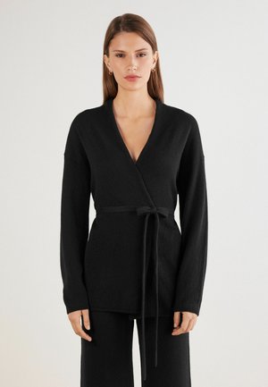 Cardigan noir en tricot avec des manches longues, décolleté en V et une ceinture à nouer à la taille. Texture douce avec des bords nets.