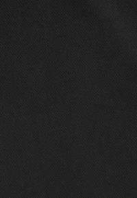 Gros plan d'un tissu noir tissé serré avec un motif discret en losanges et une surface texturée.