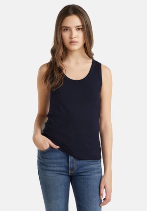 Navy blue, sleeveless tank top made of soft cotton fabric with a round neckline. Paired with denim jeans featuring visible stitching.