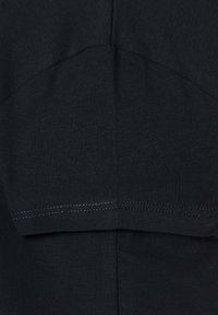 Juodas medvilnės audinys su tekstūruota paviršiaus danga ir sklandžiu siūlų apdorojimu. Dizainas apima subtilų siuvimo raštą aplink pečius.