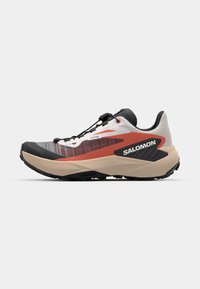 Trail running shoe in black, white, and red. Features a textured upper, secure lacing system, and a chunky outsole for grip.