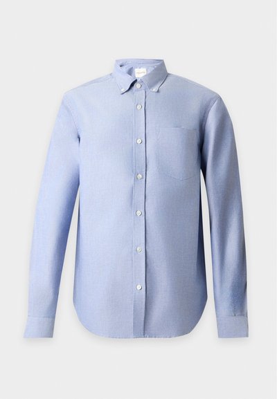 Chemise bleu clair à manches longues avec une poche avant et un col boutonné sur un fond uni clair.