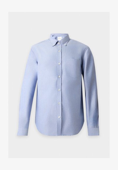Chemise bleu clair à manches longues avec une poche avant et un col boutonné sur un fond uni clair.