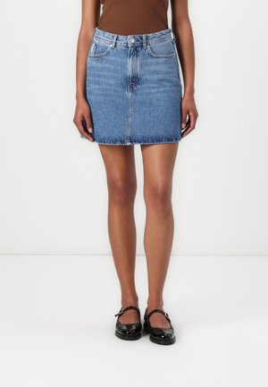 Denim mini skirt, light blue, fitted design with a raw hem. Features five pockets and a front button closure. Pairing with black shoes.