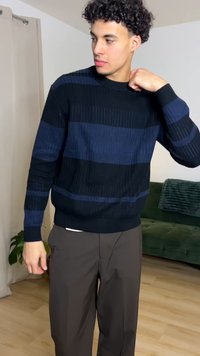 Modro-črni pulover z všitimi rebrastimi teksturami, okroglim izrezom in dolgimi rokavi, kombiniran z rjavimi ohlapnimi hlačami.