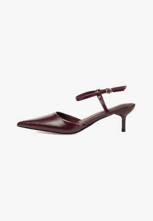 Zapato slingback de cuero burdeos oscuro con punta puntiaguda, tacón bajo de tipo kitten y una correa ajustable en el tobillo con una pequeña hebilla dorada.