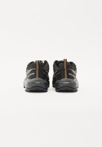Czarne buty trekkingowe z oddychającą siateczką u góry, teksturowanymi pętelkami z tyłu oraz trwałymi gumowymi podeszwami. Posiadają branding po bokach.