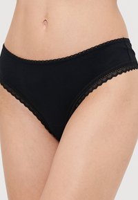 Black cotton panties with a scalloped lace trim along the waistband and leg openings, featuring a snug fit and smooth texture.