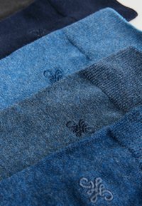 Drei Paare gestrickte Socken in verschiedenen Blautönen, mit gerippten Bündchen und dezenter Bestickung eines floralen Logos. Weicher Stoff.