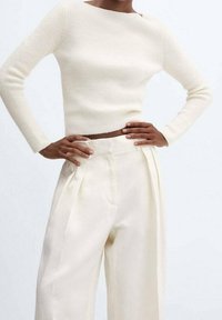 Jasno kremowy sweter z prążkowanej dzianiny z dekoltem typu łódka, zestawiony z wysokim stanem, zwiewnymi, szerokimi spodniami w kolorze kremowym z kantami.