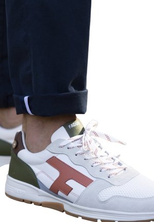Weißer Sportschuh mit grauen, grünen und braunen Akzenten; strukturiertes Mesh und glattes Leder; runde Schnürsenkel in Weiß mit rotem Muster; Logo auf der Ferse.