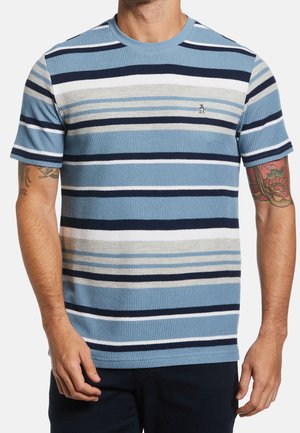 Camiseta de rayas azul con tonos variados de azul, marino, blanco y gris. Textura acanalada, cuello redondo y pequeño logo en el pecho.