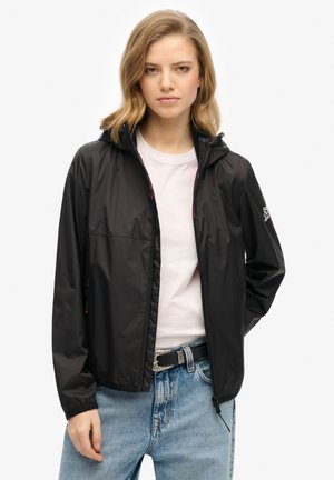 Black lightweight rain jacket with a hood, zip closure, and two side pockets. Features a smooth texture and subtle brand logo on sleeve.