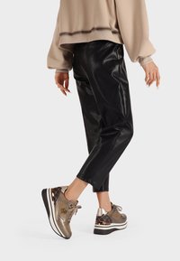 Sneakers con una toma metallic beige, dettagli in pelle e un retro con motivo. Presentano una suola intermedia spessa bianca e una suola esterna in gomma nera.