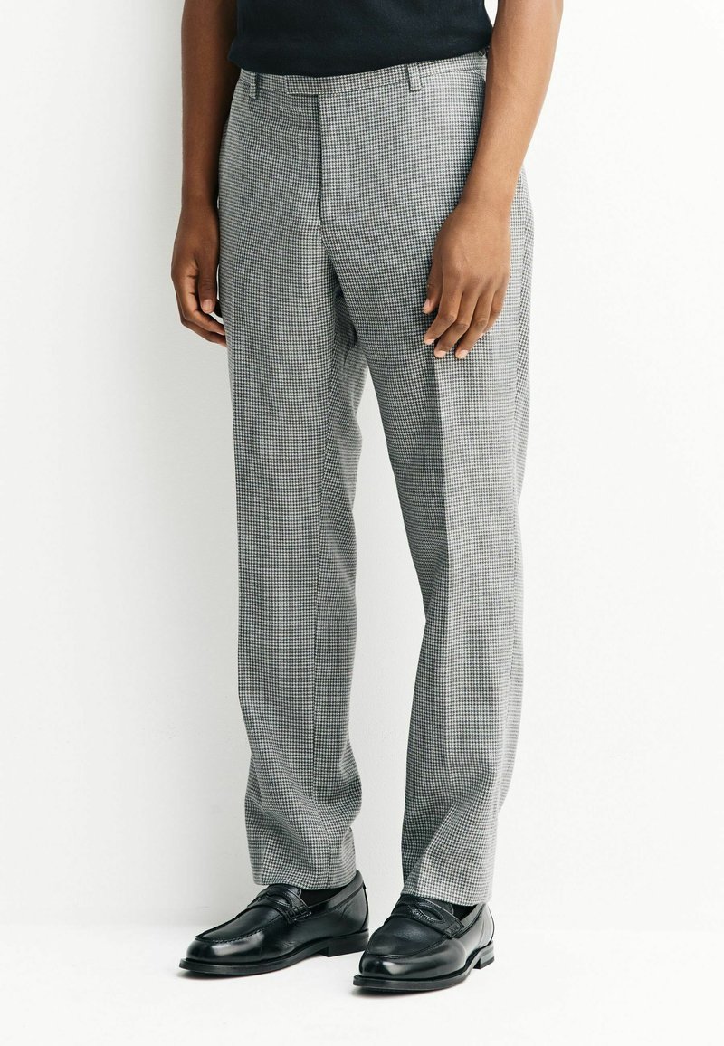Gray checkered trousers made of woven fabric, tailored fit, featuring a flat front and side pockets. Paired with black leather shoes.