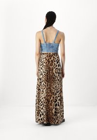 Denim bodice dengan tali yang dapat disesuaikan bertransisi menjadi rok panjang dengan pola leopard dalam nuansa beige dan cokelat, dengan tekstur yang halus.