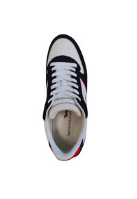 Sneaker bianco e nero con accenti rossi. Presenta una tomaia in tessuto testurizzato, lace bianchi piatti e un colletto imbottito. Logo visibile all'interno.